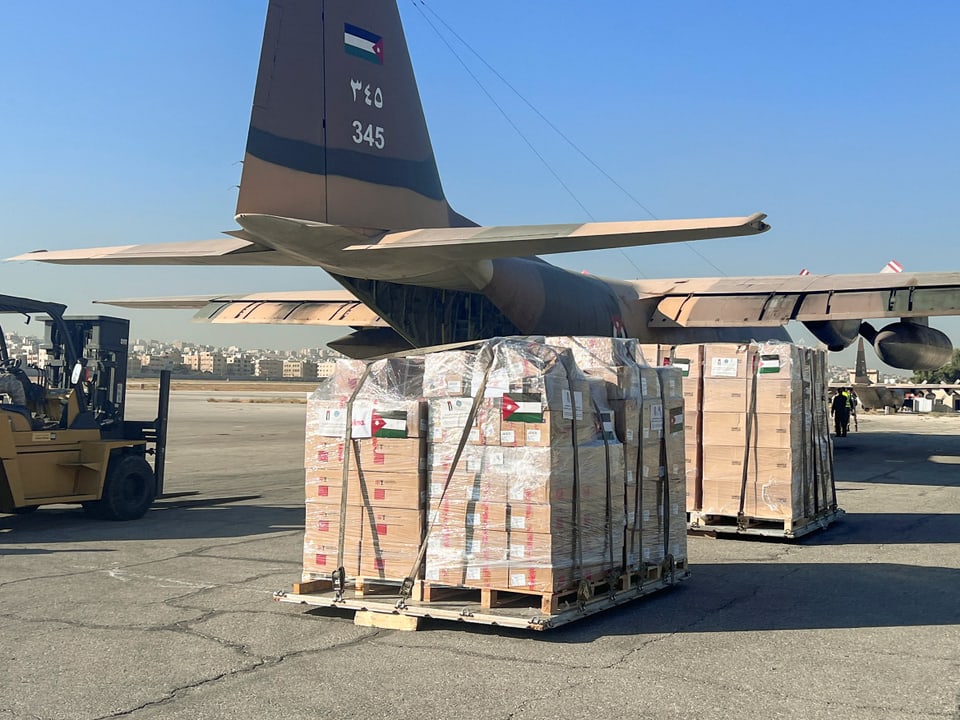 Kisten von Hilfsgütern stehen vor einem Flugzeug.