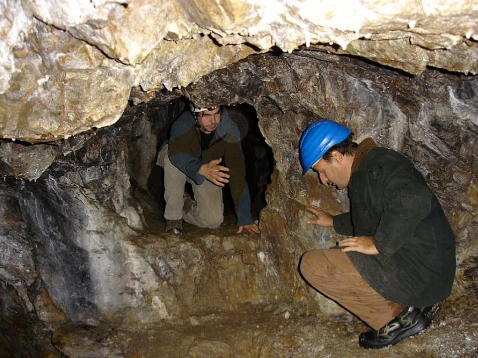 Zwei Männer gucken auf die Höhlenwand.