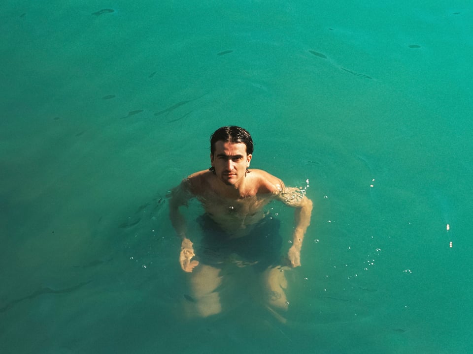 Ein junger Mann schwimmt in türkisem Wasser