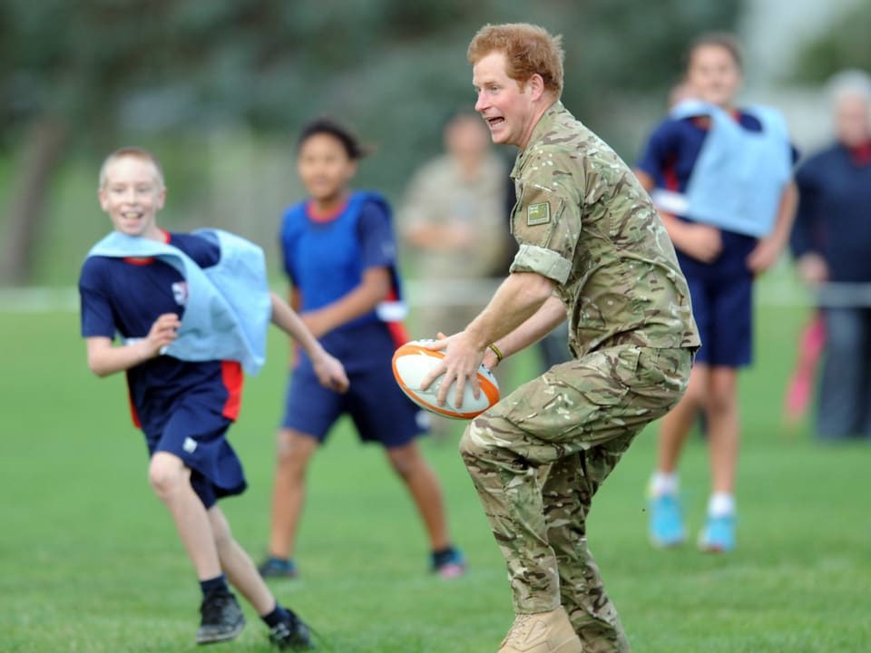 Prinz Harry spielt mit einem Rugby-Ball.