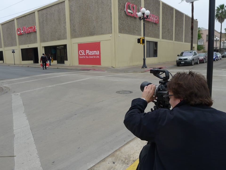 Kameramann filmt Fassade eines Blutplasma-Spendezentrums.