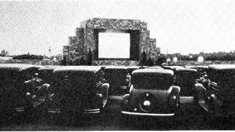 Ein Schwarzweissbild aus den 1930er-Jahren. Eine grosse Leinwand, davor viele alte Autos.