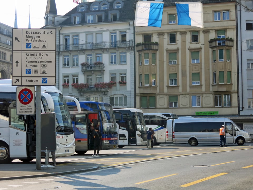 Carparkplatz Löwenplatz mit parkierten Touristenbusse und wartenden Touristen. 