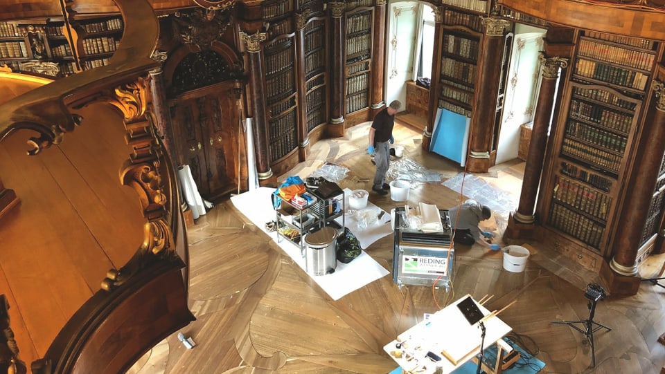 Blick in die Stiftsbibliothek, deren Boden gebürstet und poliert wird.