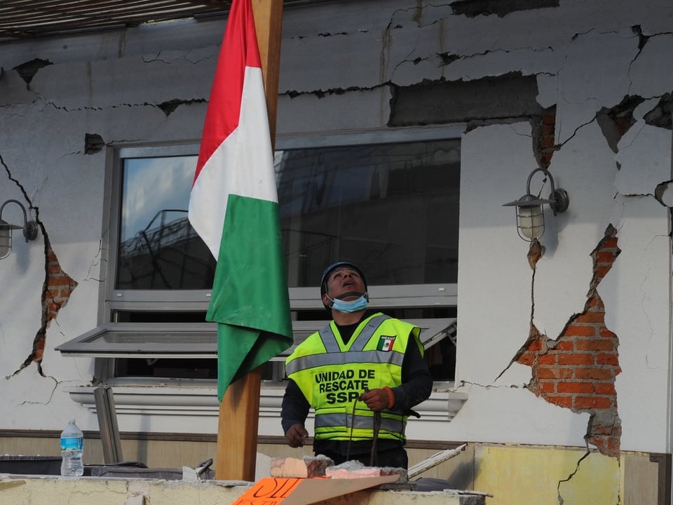 REttungskraft vor eingestürzter Schule mit Fahne