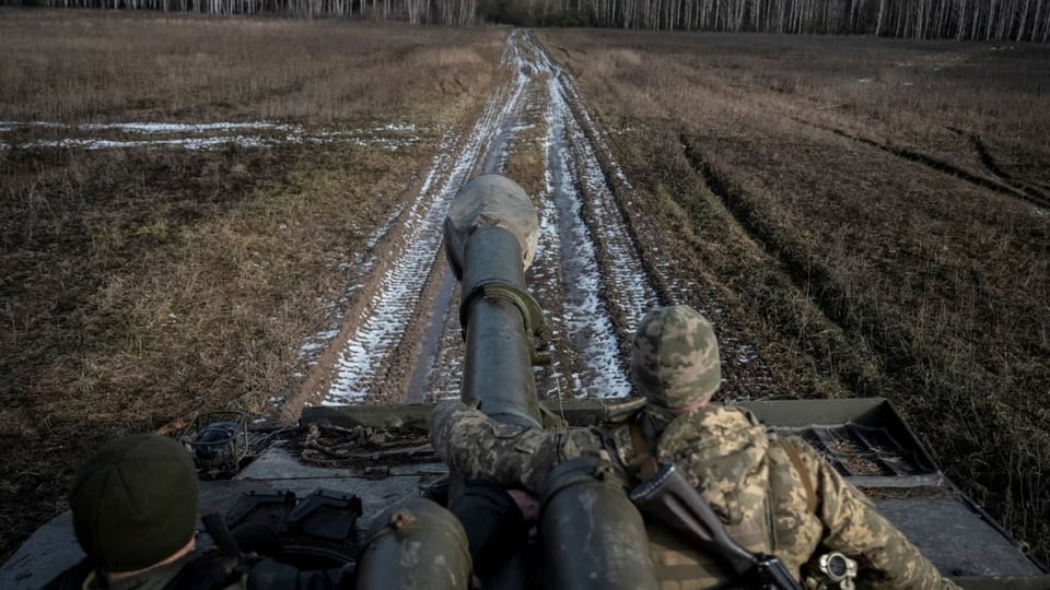 Ein Panzer und seine Besatzung. Es sieht so aus, als ob man selber auf dem Panzer sitzen würde. Vorne ein langer Weg.§