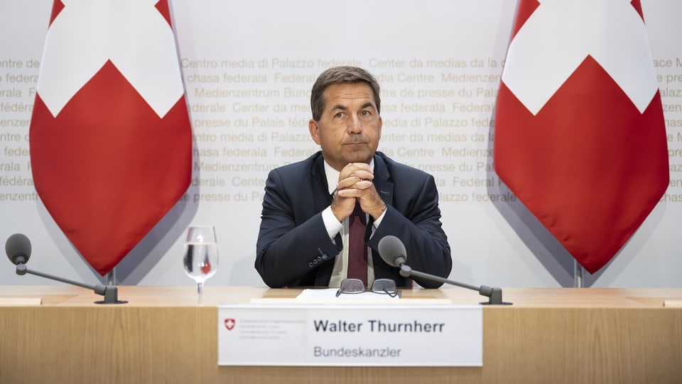 Walter Thurnherr sitzt vor einem Mikrophon. 