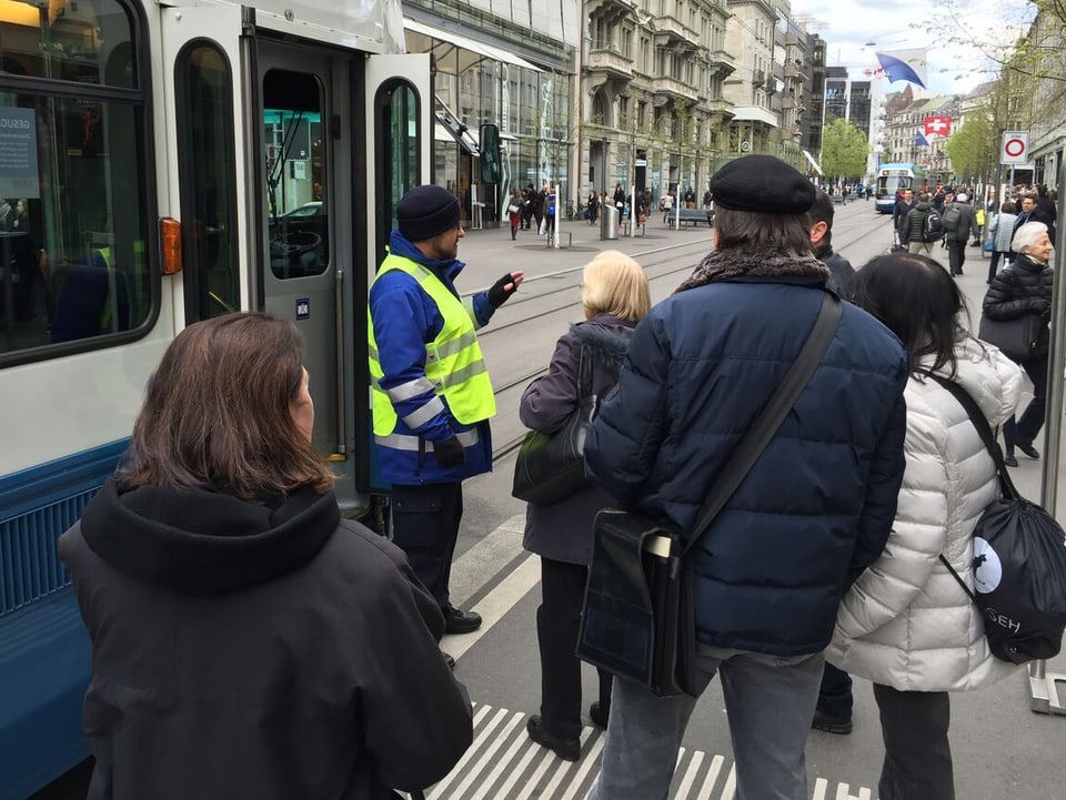 Menschen stehen vor einem Tram mit offener Türe