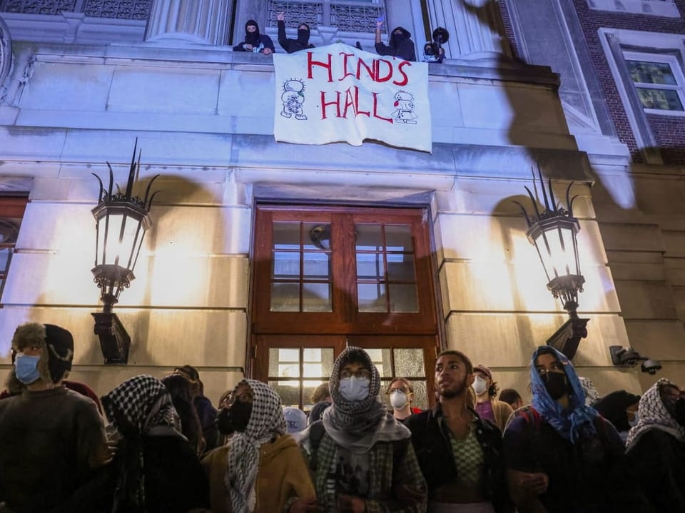 Protestierende mit Gesichtsmasken und Kopftüchern vor dem Hinds Hall bei Nacht.