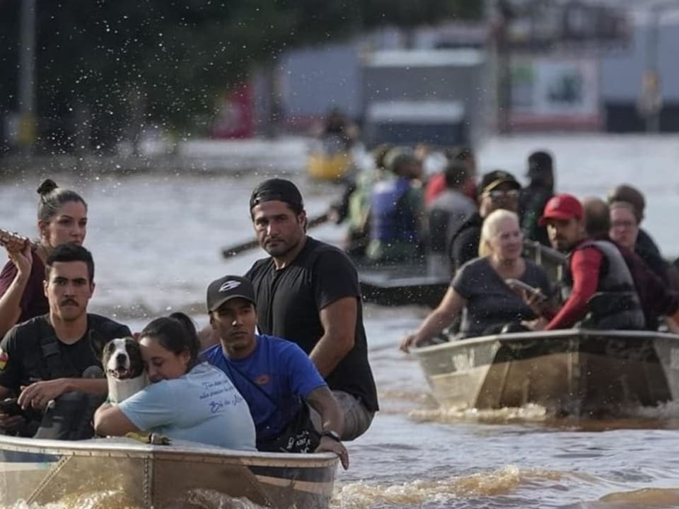 Menschen in Booten auf einem überfluteten Strassenzug