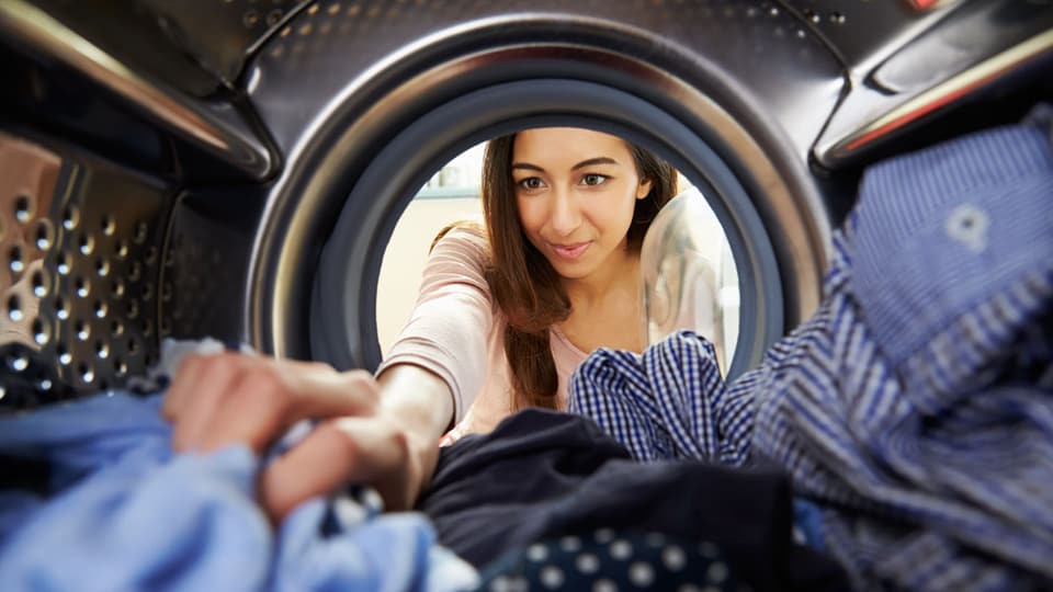 Frau räumt Waschmaschine aus.