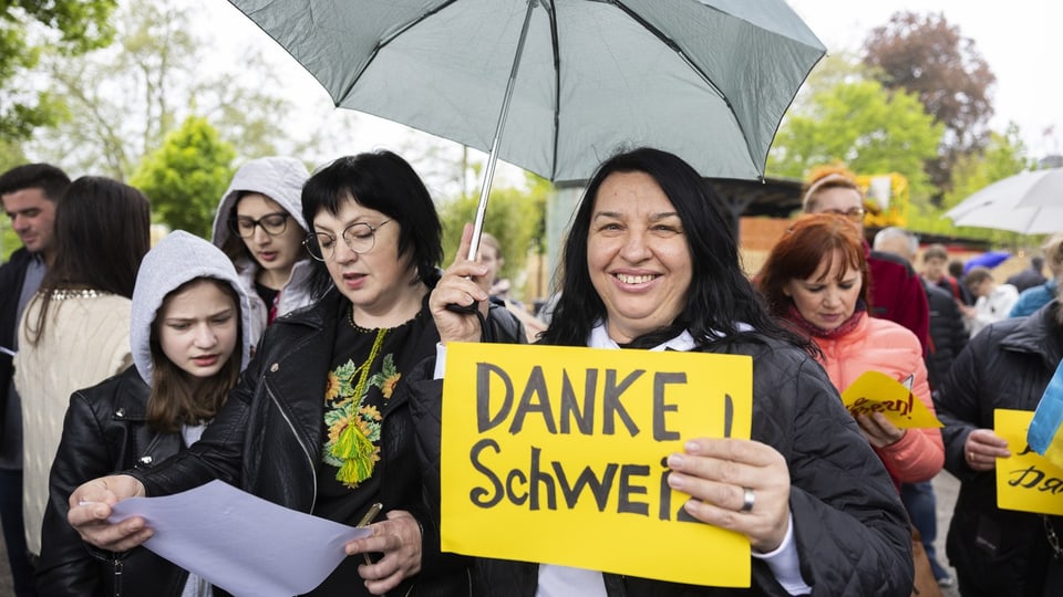 Ukrainische Frauen an Kundgebung in der Schweiz. Eine Frau hält ein gelbes Schild mit der Aufschrift «Danke Schweiz!»