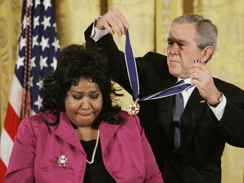 George W. Bush legt Medaille um Aretha Franklins Hals.