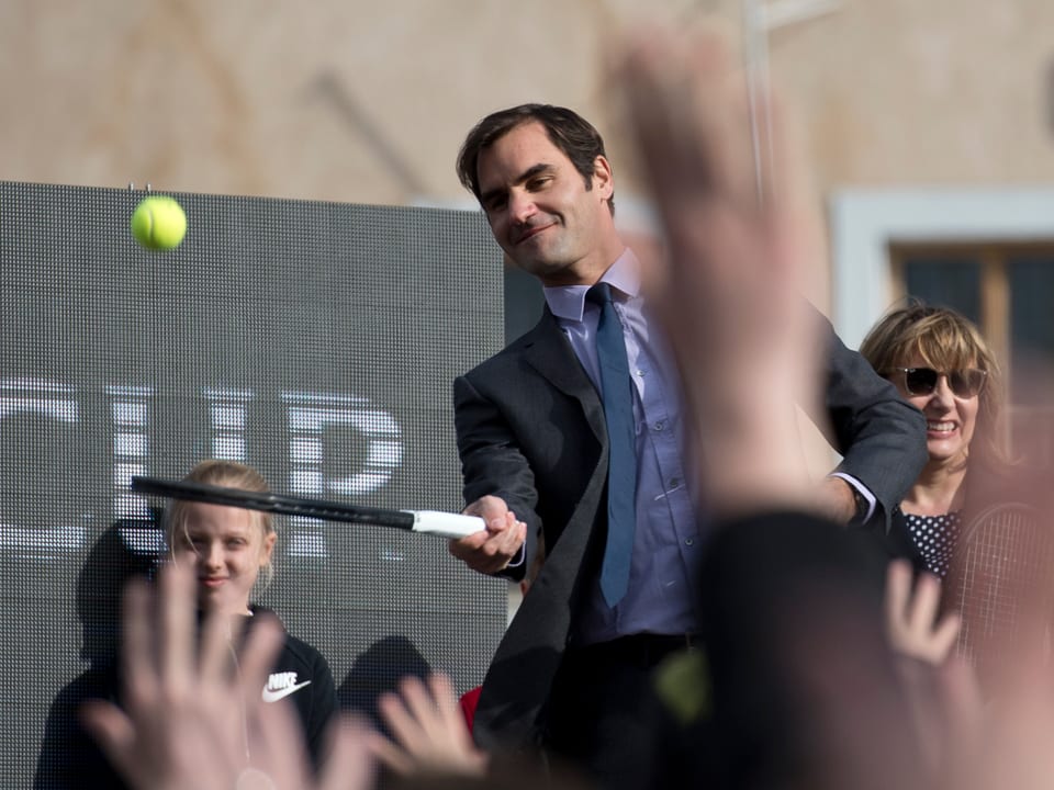 Federer schlägt einen Tennis Ball in die jubelnde Menge.