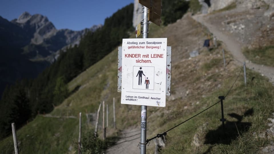 Tafel mit «gefährlicher Bergweg» und Hinweis, Kinder mit einer Leine zu sichern