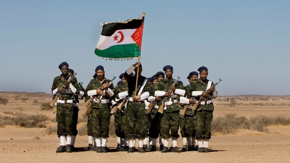 Eine Gruppe militärisch gekleideter Männer mit Waffen und der Flagge der Westsahara