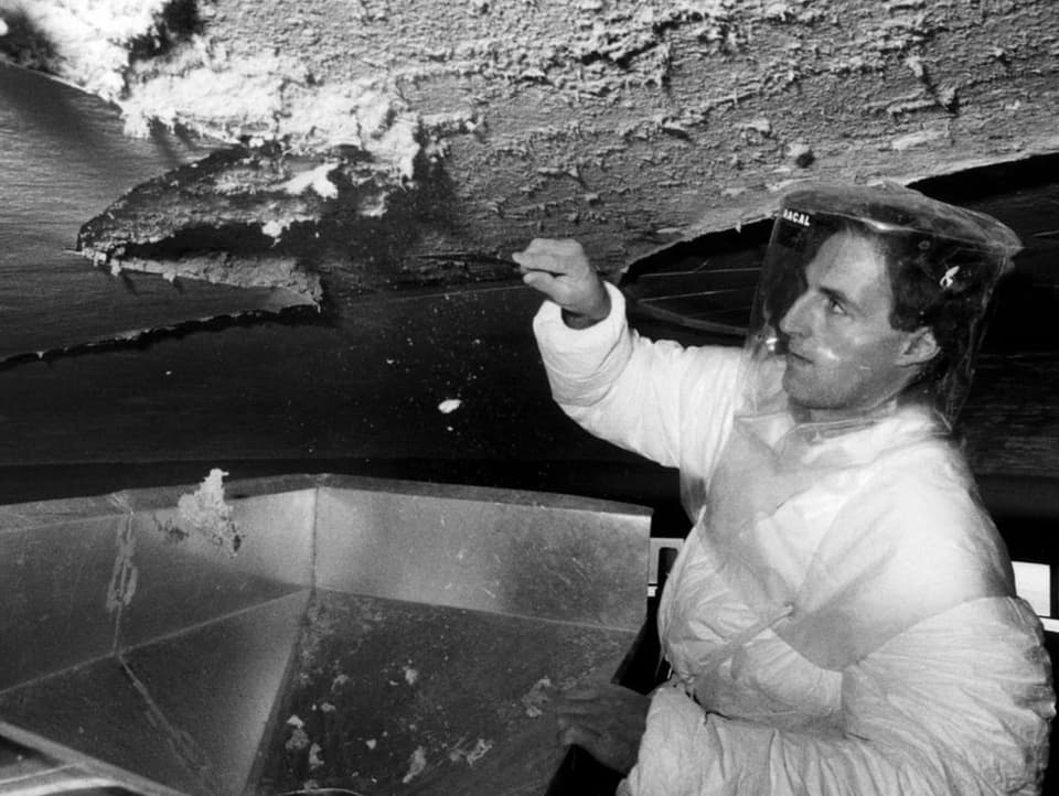 Man wearing protective clothing removing asbestos residue (black and white)