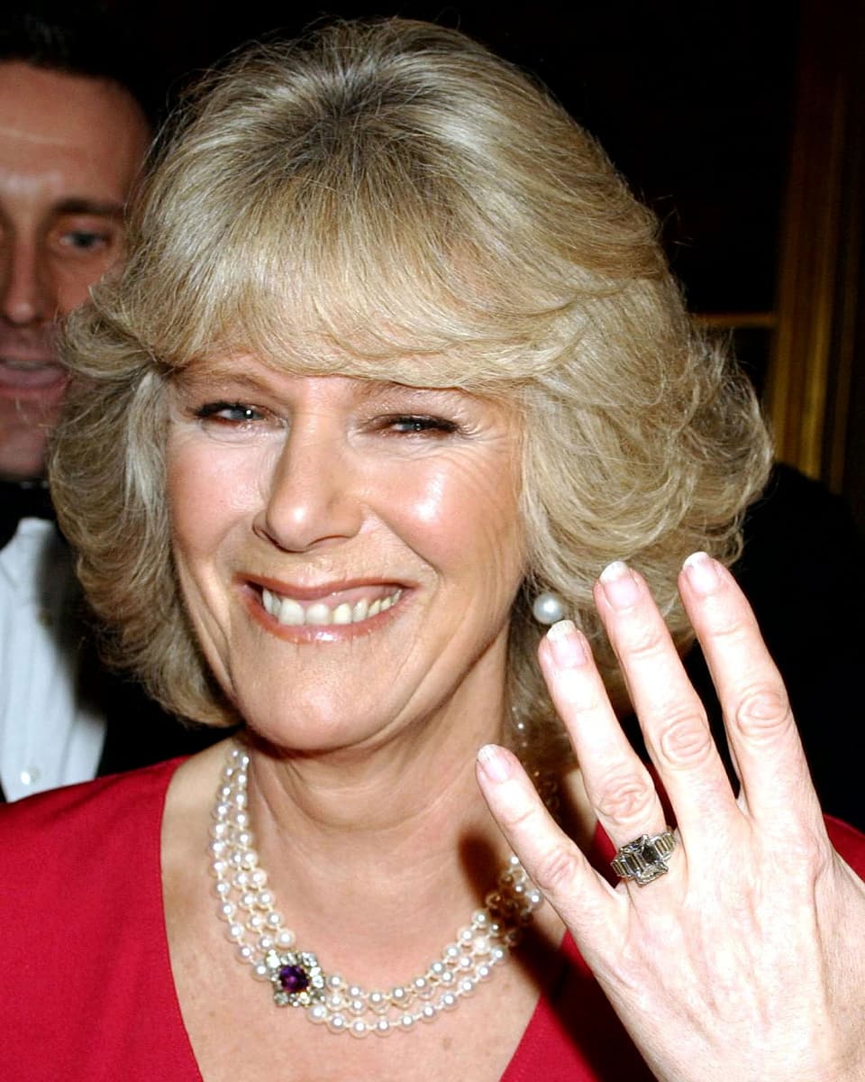 Camilla Parker Bowles zeigt lachen ihre linke Hand mit Diamantring.