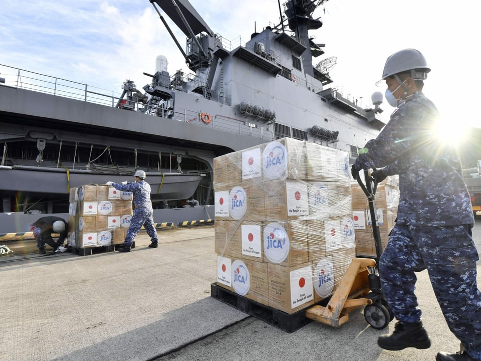 Ein Japaner verlädt Hilfsgüter in ein Miltiärschiff.