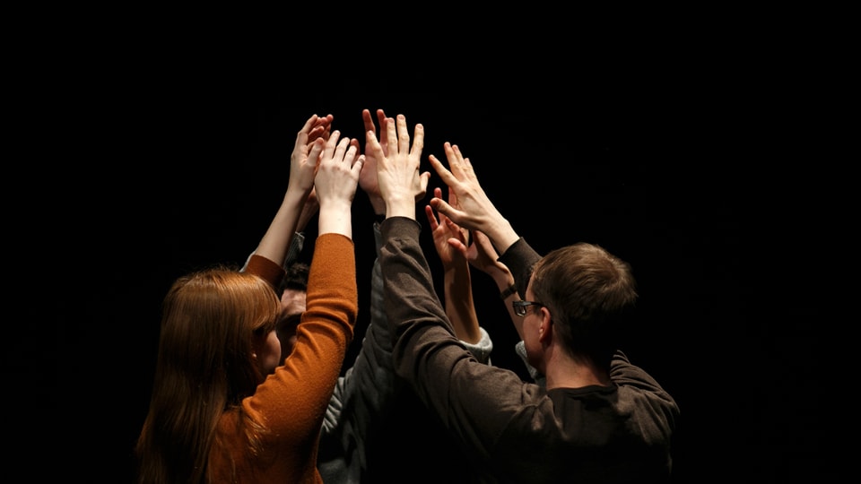Fünf Leute heben im Kreis die Hände und bilden ein Menschenzelt.