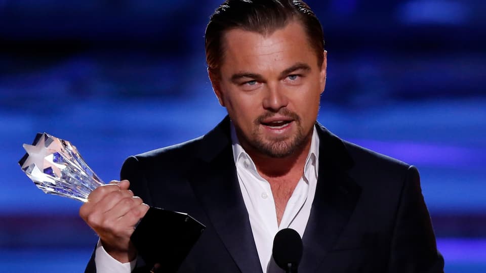 Leonardo DiCaprio mit Preis in der Hand am Mikrophon stehend.