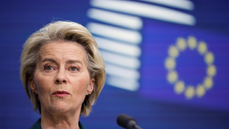 Frau spricht bei einer Pressekonferenz vor einem EU-Flaggenhintergrund