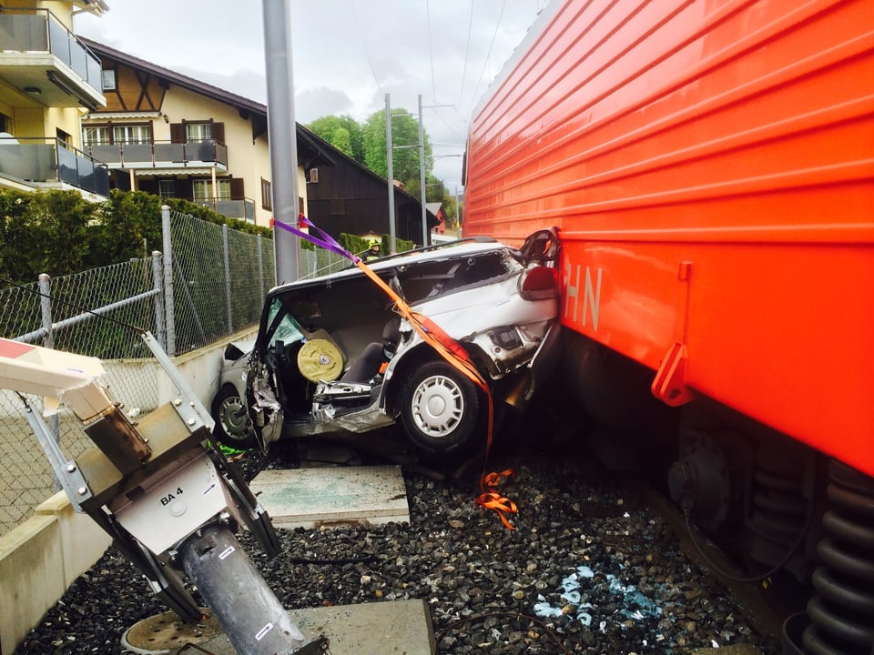 Das graue Auto, total zerstört, knallte offenbar nach dem Aufprall mit dem Zug in die Mauern. Neben ihm der rote Zug. 