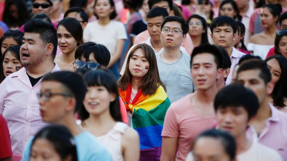 Eine Frau mit Regenbogenflagge inmitten einer Menschenmenge