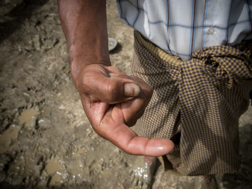 Ein Mann in Myanmar putzt sich mit dem Finger die Zähne.