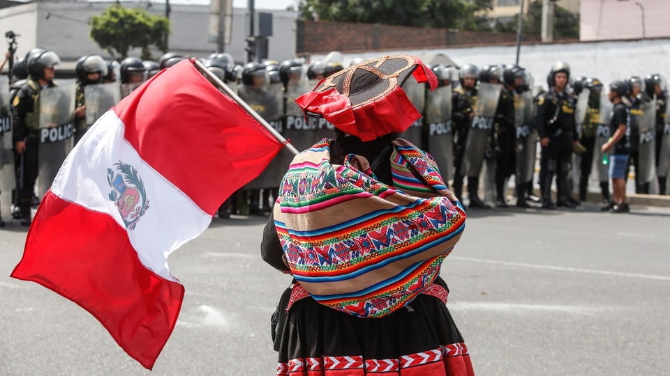 An indigenous woman carries a Peruvian flag during the 2023 Tina Poluarte protest in Lima.