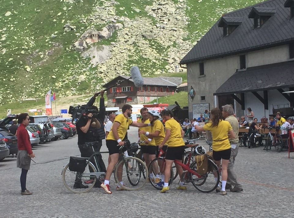 Velofahrer in gelbem Trikot stehen mit ihren Rädern auf dem Gotthardpass zusammen.