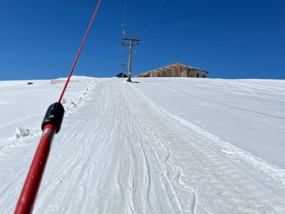Blick auf einen verschneiten Skilift mit Blick die Piste hinauf.