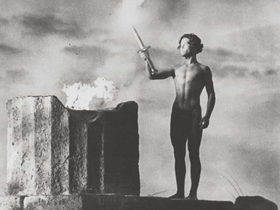 Ein Mann entzündet das olympische Feuer,