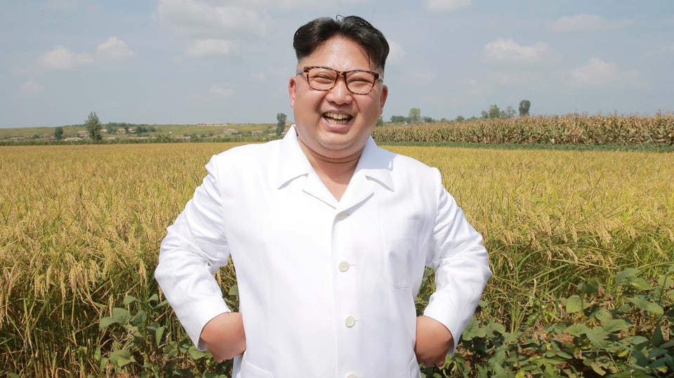 Kim steht vor einem Kornfeld und lacht.