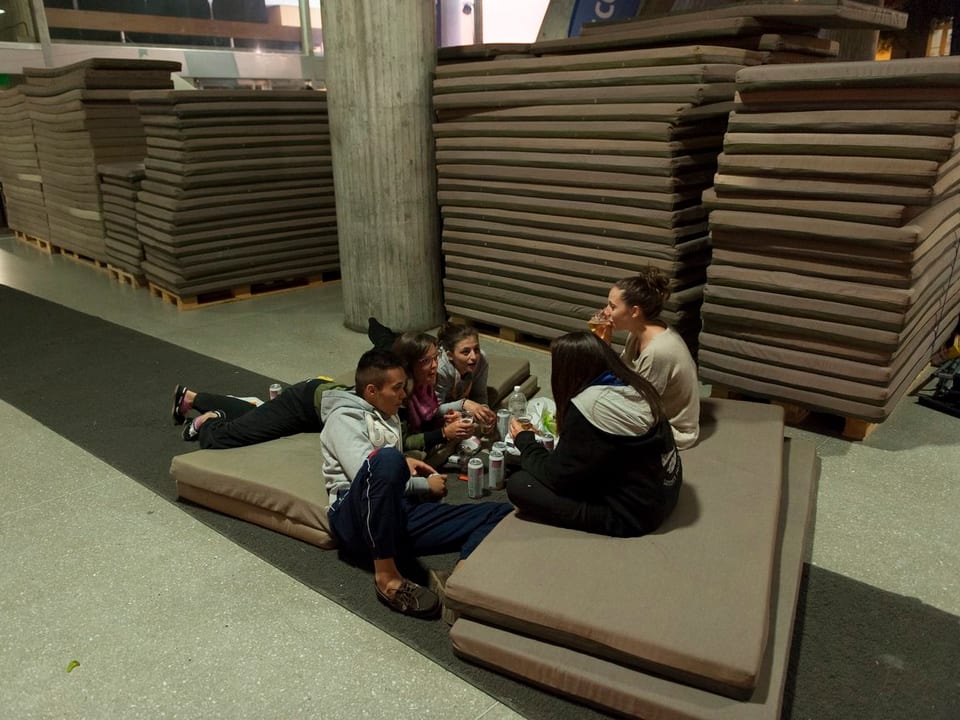 Jugendliche sitzen vor der improvisierten Notschlafstelle im Kongresshaus in Biel auf Matrazen. 