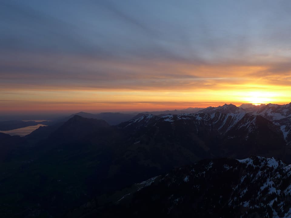 Flugaufnahme einer Sonnenaufgang-Stimmung mit See und Bergen. 