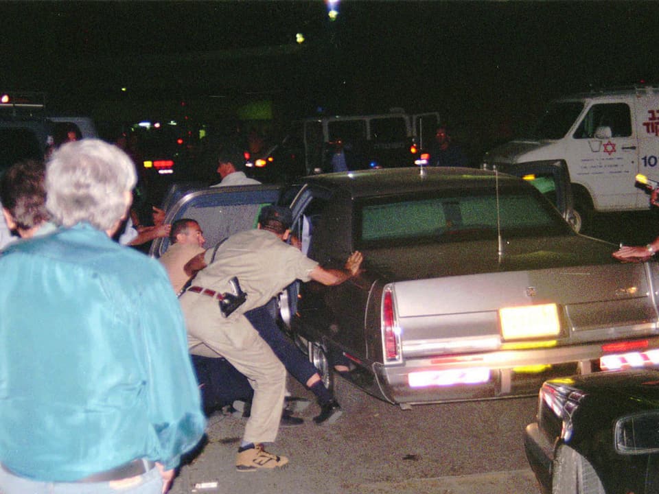 Personen versuchen Rabin in eine Limousine zu legen.