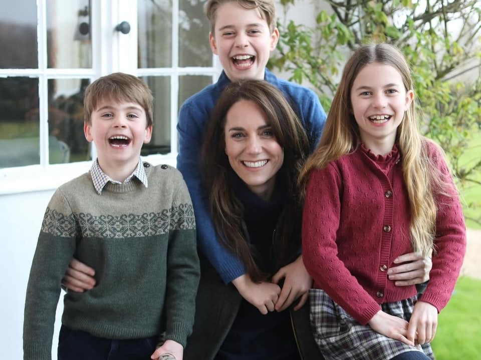 Prinzessin Kate sitzend mit ihren drei Kindern. Alle lachen in die Kamera.