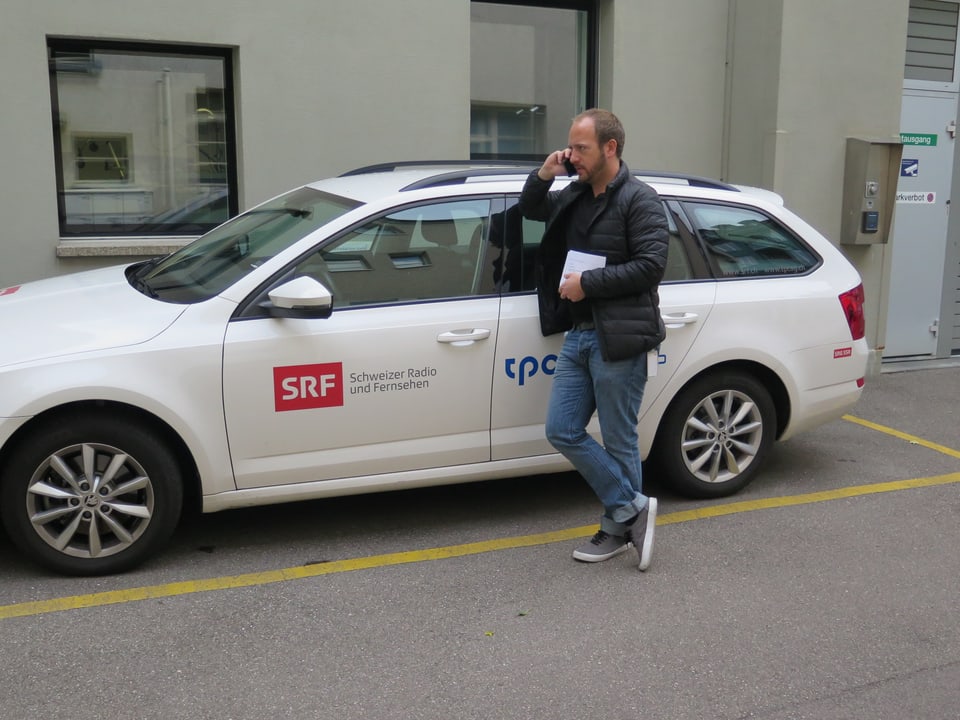 Matthias Haymoz telefoniert vor dem SRF-Auto.