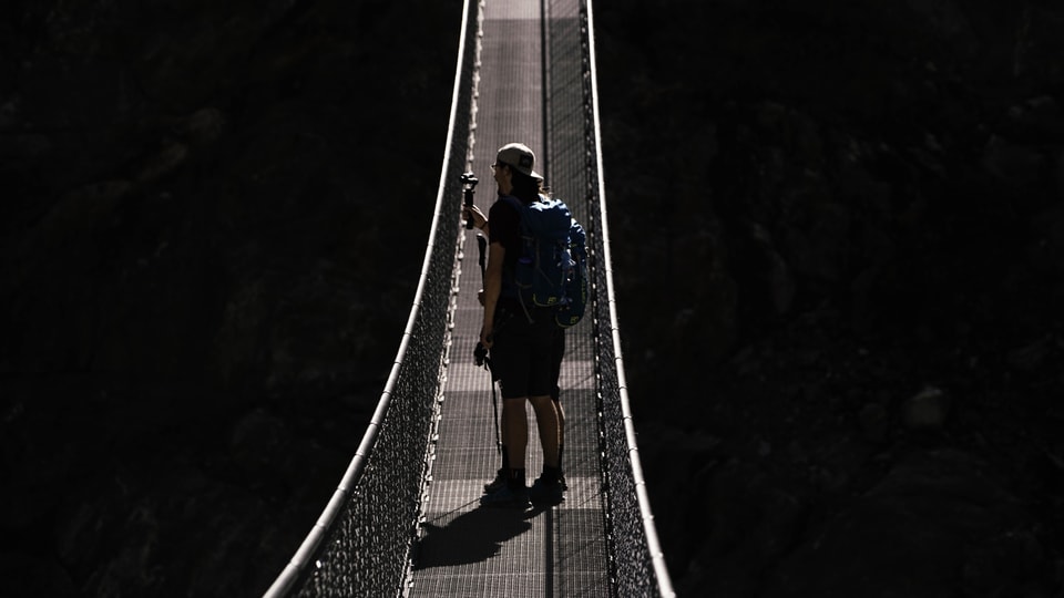 Wanderer machen Fotos auf einer Hängebrücke.