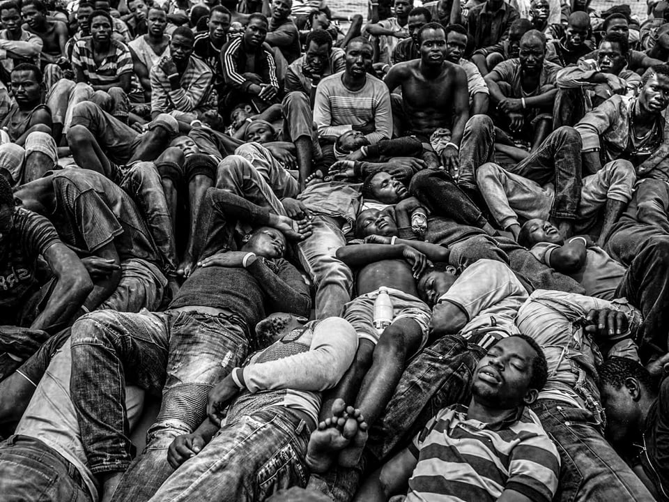 Viele Westafrikaner liegen zusammengepfercht auf einem Rettungsboot.