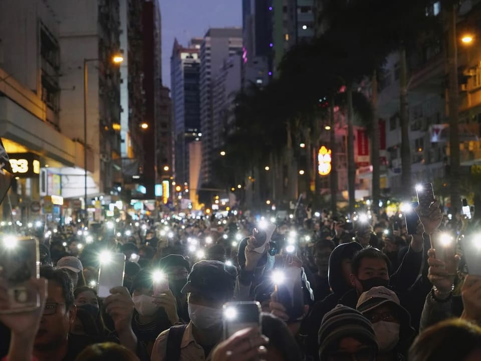 Menschen in den Strassen lassen ihre Handy-Taschenlampen erleuchten.