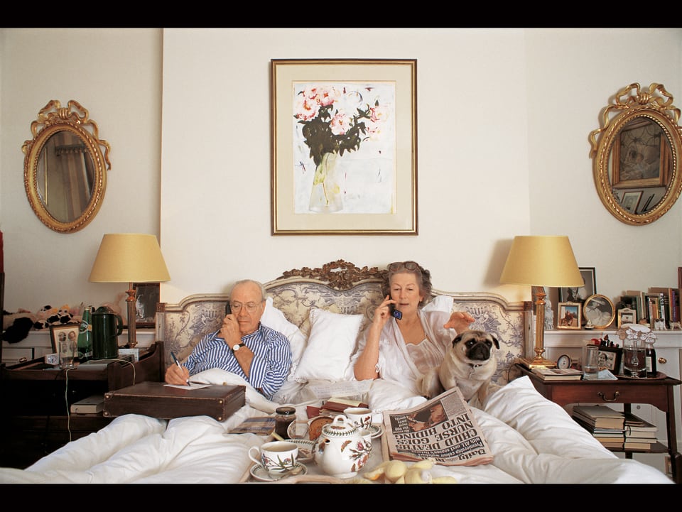 zwei ältere Menschen in ihrem Bett, jede mit Telefon in der Hand