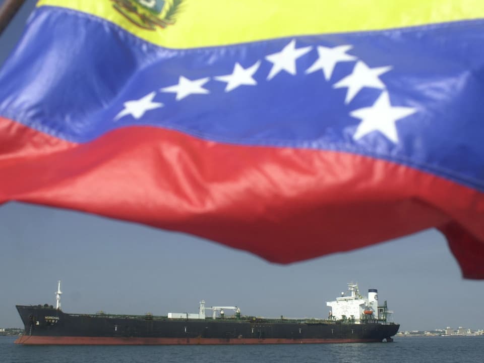 Die Flagge Venezuelas weht vor einem Frachtschiff. 