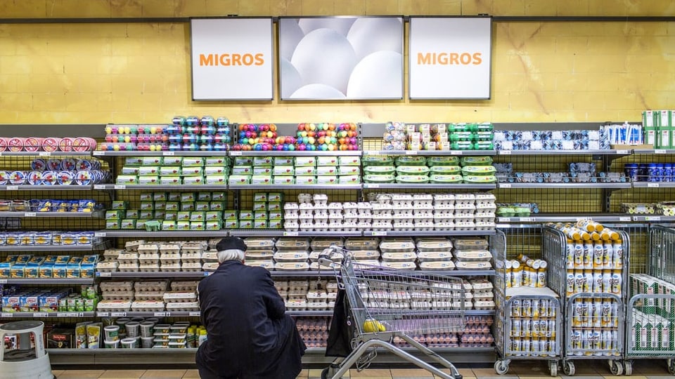 Betagter Mann kniet vor Regal in Migros-Filliale