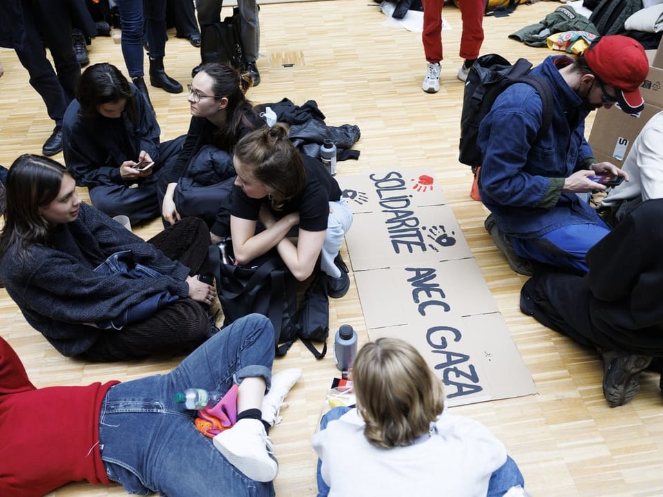 Gruppe junger Menschen sitzt auf dem Boden und bereitet Protestplakate vor
