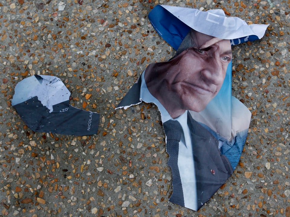 official campaign poster for French President and UMP political party candidate Nicolas Sarkozy is seen on the pavement in front of a polling station in Tulle May 6, 2012. 