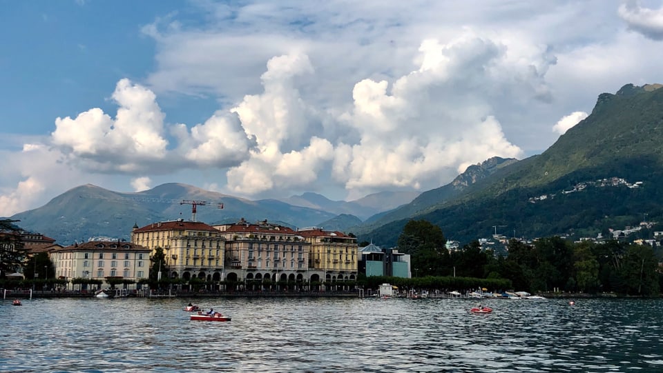 Blick über den See auf Lugano, dahinter dicke Quellwolken.