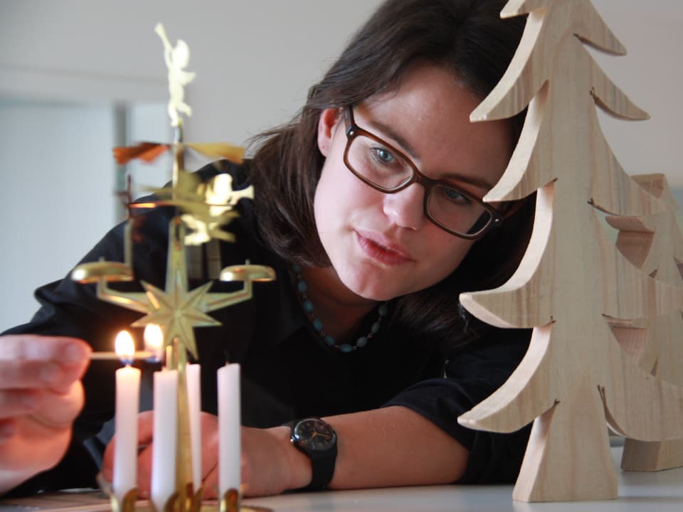 Fränzi Haller zündet eine der vier Kerzen an, die unter goldenen Engeln stehen.