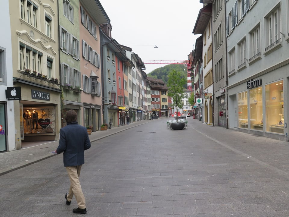 Eine Strasse in einer Stadt. Links und rechts sind Geschäfte.